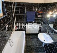 Ein Badezimmer im Einfamilienhaus mit schwarzen Fliesen, einer Badewanne und einem Spiegel.