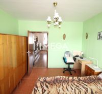 Ein Zimmer mit grünen Wänden, einem Holzschrank und einem Schreibtisch in einer Vierzimmerwohnung.