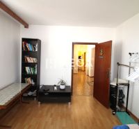 Ein Zimmer in einer 4-Zimmer-Wohnung mit einem Bücherregal und einem Boden in Holzoptik.