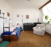 Ein Zimmer in einer 4-Zimmer-Wohnung mit einem Bett, einem Sessel und einem Boden in Holzoptik.