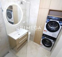 Badezimmer in einer 3-Zimmer-Wohnung mit Waschmaschine, Trockner und beleuchtetem rundem Spiegel.