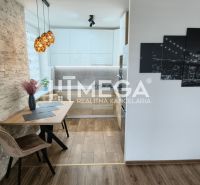 Eine Wand mit dekorativem Stein und eine Küche mit einem Boden in Holzdekor in einer 3-Zimmer-Wohnung.