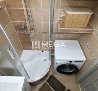 Badezimmer mit Dusche und Waschmaschine in einer 3-Zimmer-Wohnung, mit braunen Fliesen.