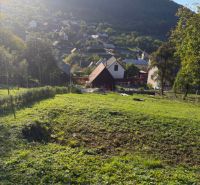 Ein Baugrundstück in Košecké Podhradie, umgeben von Natur und Häusern, unter den Gipfeln der Berge.