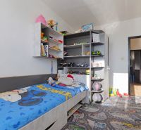 Kinderzimmer in einer 3-Zimmer-Wohnung mit einem Bett und Regalen voller Spielzeug und Bücher.