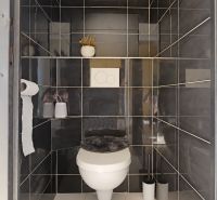 Badezimmer in einer 3-Zimmer-Wohnung mit dunkelgrauen Fliesen und weißer Sanitärausstattung.