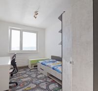 Kinderzimmer in einer 3-Zimmer-Wohnung mit Bett und Schreibtisch auf einem bunten Teppich.