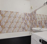 Badezimmer mit Badewanne und Waschmaschine in einer 3-Zimmer-Wohnung, Fliesen mit auffälligem Muster.