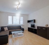 Wohnzimmer mit schwarzem Sofa, Schränken und Boden in Holzoptik, 3-Zimmer-Wohnung.