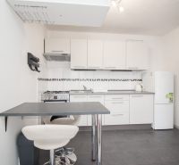 Küche in einer 2-Zimmer-Wohnung mit weißen Schränken und einem Esstresen.