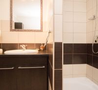 Badezimmer mit Waschbecken, Waschmaschine und Duschkabine in einer 2-Zimmer-Wohnung.