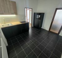 Küche in einer 2-Zimmer-Wohnung mit schwarzen Schränken und strukturiertem Boden.