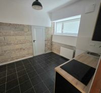 Küche in einer 2-Zimmer-Wohnung mit Ziegelverkleidung und schwarzem Fliesenboden.