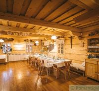 Innenraum eines Einfamilienhauses mit Holzboden, gedeckten Tischen und Holzmöbeln.