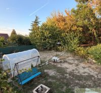 Der Garten bei der Hütte in Nové Zámky mit einer Schaukel und einem Folientunnel, umgeben von Grün.