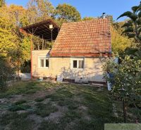 Ein Ferienhaus in Nové Zámky, umgeben von Grün, mit einem roten Dach in einer natürlichen Umgebung.