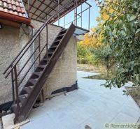 Das Äußere der Hütte in Nové Zámky mit einer Metalltreppe und einer von Grün umgebenen Terrasse.