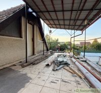 Die Terrasse der Hütte in Nové Zámky mit Unordnung und Baumaterial, ein ruhiger Garten im Hintergrund.