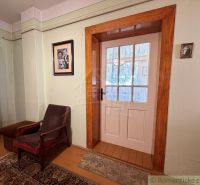 Ein Zimmer in einem Einfamilienhaus mit einem Sessel, einem Teppich und Glastüren.