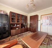 Wohnzimmer in einem Einfamilienhaus mit Schränken, einem Tisch und einem gemusterten Teppich.