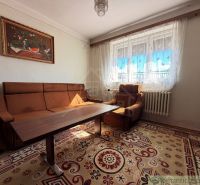 Wohnzimmer in einem Einfamilienhaus mit braunem Sofa und Vorhängen.