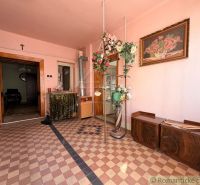 Innenraum eines Einfamilienhauses mit rosa Wänden, Blumendekoration und Schachbrettboden.