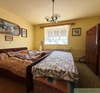 Schlafzimmer im Einfamilienhaus mit Bett und Wohnwand, an der Wand Bilder.