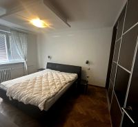 Schlafzimmer in einer 2-Zimmer-Wohnung mit Bett, Kleiderschrank und Boden in Holzoptik.