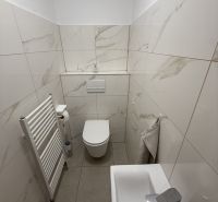 Badezimmer in einem Einfamilienhaus mit weißen Fliesen und Waschbecken.