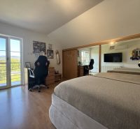 Schlafzimmer in einem Einfamilienhaus mit Holzboden, Spiegelschrank und Balkontüren.