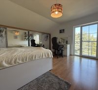 Schlafzimmer mit einfachem Betthaupt, Schreibtisch und Boden in Holzoptik.