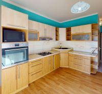 Küche mit Holzelementen und türkisfarbener Wand in einer 3-Zimmer-Wohnung.