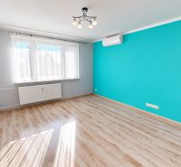 Ein Zimmer in einer 3-Zimmer-Wohnung mit blauer Wand und Boden in Holzoptik.