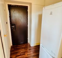 Ein Interieur mit einem Kühlschrank und einem Holzboden in einem Einzimmerapartment.