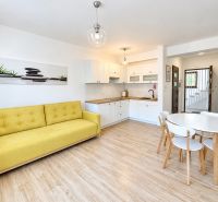 Wohnzimmer in einer Einzimmerwohnung mit Holzboden und gelbem Sofa.