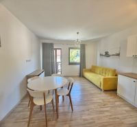 1-Zimmer-Wohnung mit Holzboden, gelbem Sofa und weißen Möbeln.