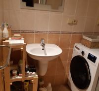 Badezimmer mit Spiegel und Waschmaschine in einer 2-Zimmer-Wohnung mit beigen Fliesen.
