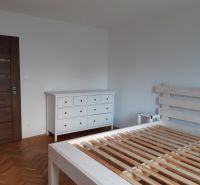 Schlafzimmer mit weißen Möbeln und Boden in Holzoptik in einer 2-Zimmer-Wohnung.