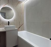 Badezimmer mit rechteckiger Badewanne und rundem Spiegel in einer 4-Zimmer-Wohnung.
