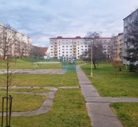 Plattenbau-Wohnblöcke umgeben eine Rasenfläche mit Gehwegen und einem Einzimmerapartment.