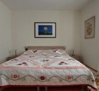 Schlafzimmer in einer 3-Zimmer-Wohnung mit gemustertem Bettüberwurf und Wanddekorationen.