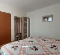 Schlafzimmer mit Bett, heller Wand, Holzschrank und Boden mit Holzdekor in einer 3-Zimmer-Wohnung.