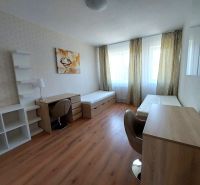 Ein Zimmer mit zwei Betten, Tischen und einem Boden mit Holzdekor in einer 3-Zimmer-Wohnung.