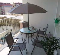 Balkon einer 3-Zimmer-Wohnung Nad Plážou in Banská Bystrica mit Sitzgelegenheit und Sonnenschirm.