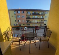 Der Balkon einer 2-Zimmer-Wohnung in Vlčkovce mit Tisch und Stühlen, Blick auf das Wohngebäude.