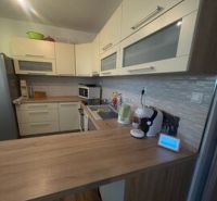 Küche in einer 2-Zimmer-Wohnung mit Holzboden und hellen Möbeln.