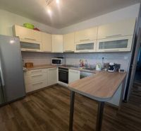 Küche mit hellen Schränken und Holzboden in einer 2-Zimmer-Wohnung.