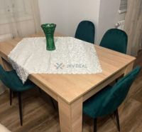 Esstisch mit einer Vase und grünen Stühlen, Holzboden in einer 2-Zimmer-Wohnung.