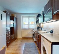 Küche in einer 2-Zimmer-Wohnung mit Holzboden und eingebauten Geräten.