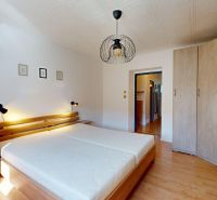 Schlafzimmer mit Doppelbett, Kleiderschrank und Holzboden in einer 2-Zimmer-Wohnung.